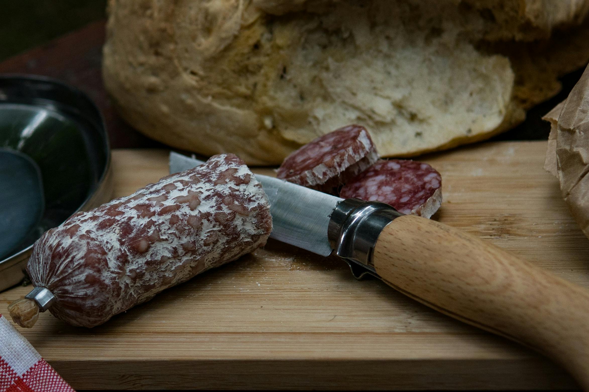 tagliere con salame intero e affettato con coltello di legno