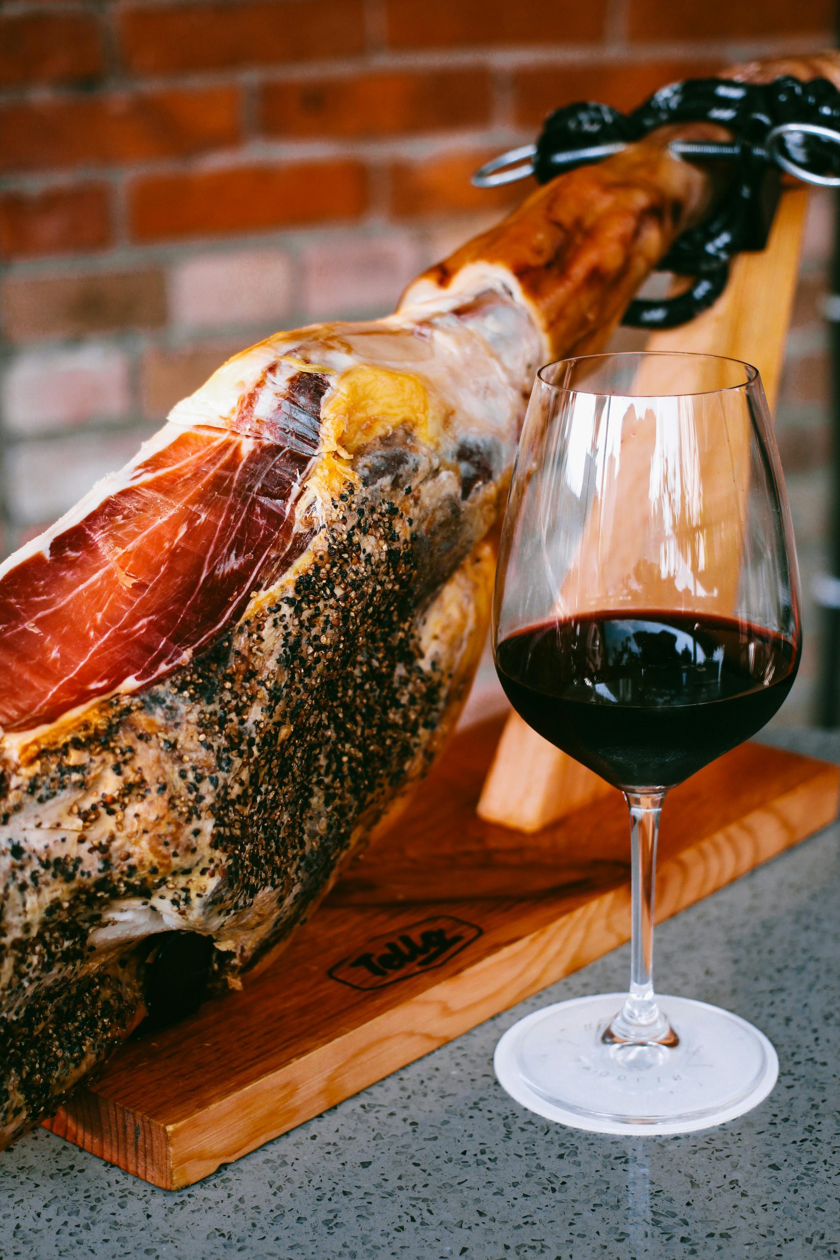 prosciutto intero su sostegno da taglio e un bicchiere di vino rosso